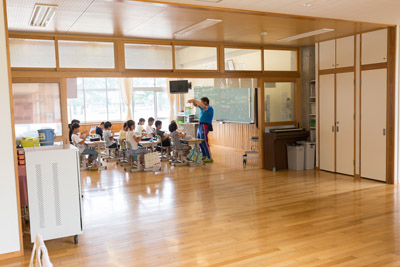 大きく解放された教室で授業を受ける児童たちの写真