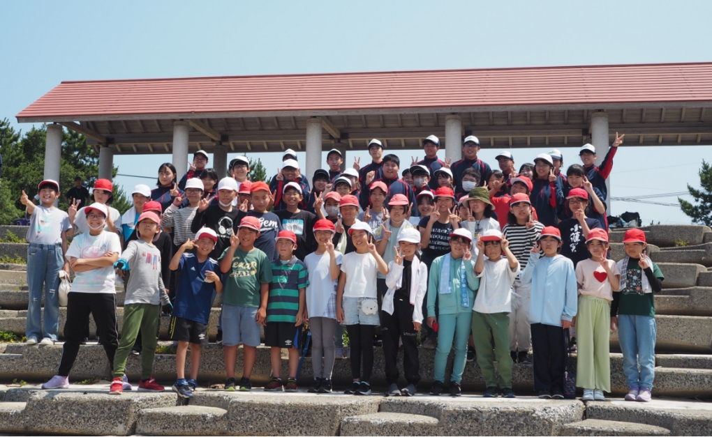 笑顔で石段の上に立つ、赤白帽を被った50名ほどの小学生・中学生・高校生たちの写真