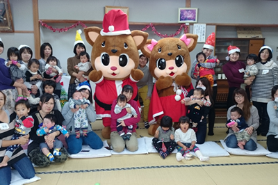 トナカイのキャラクターの着ぐるみと一緒に写る子育て広場での記念写真