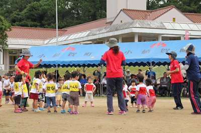 保育園のグラウンドで先生と幼児たち運動会をしている写真
