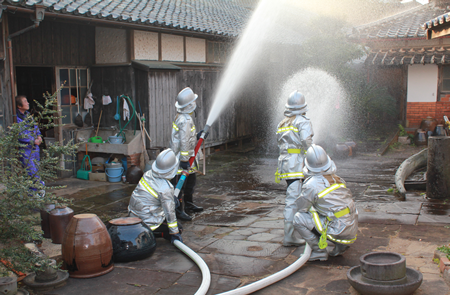 消防隊がホースで放水訓練をする写真